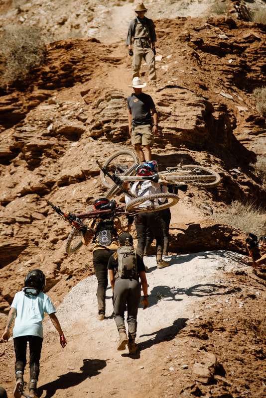 Female mountain bikers carrying their bikes up Red Bull Rampage